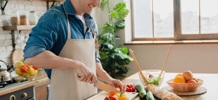 A man prepping vegetables on a kitchen island